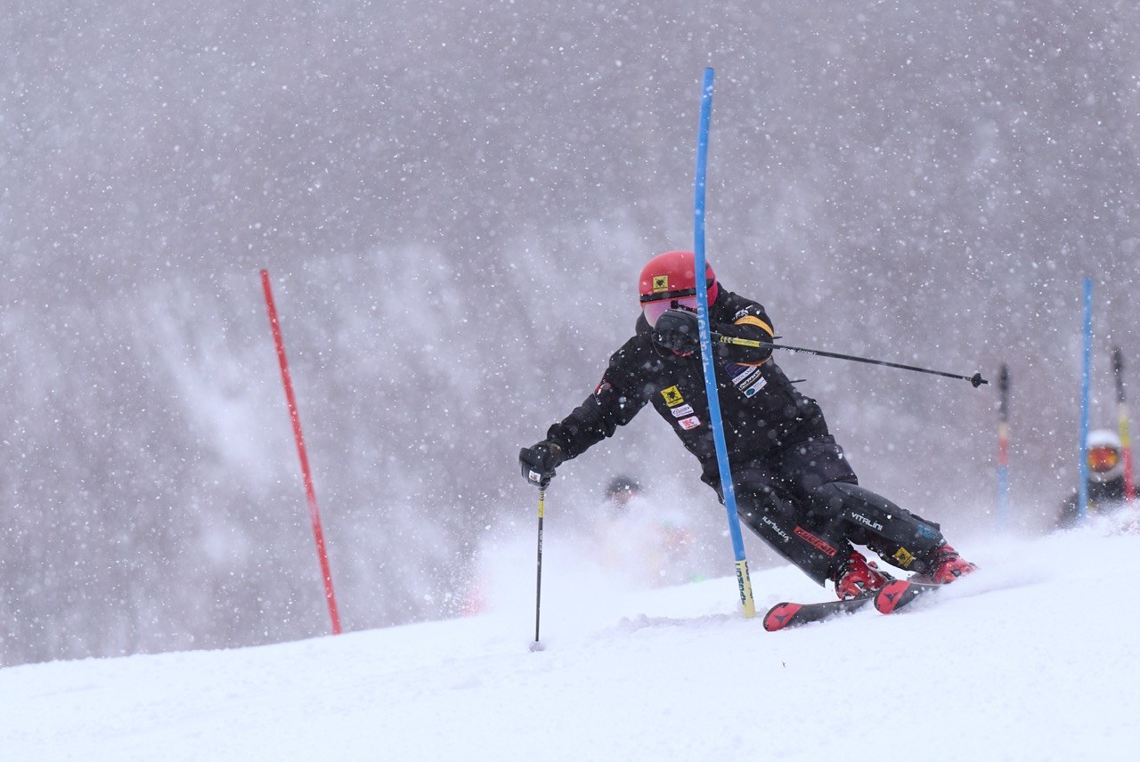 降雪のなかスラロームのポールを滑るレーサー